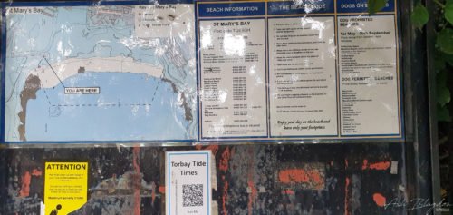 a sign with beach warnings and information