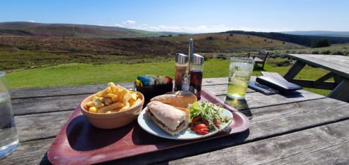 a table with a plate of food and a drink with a view at Warren House Inn